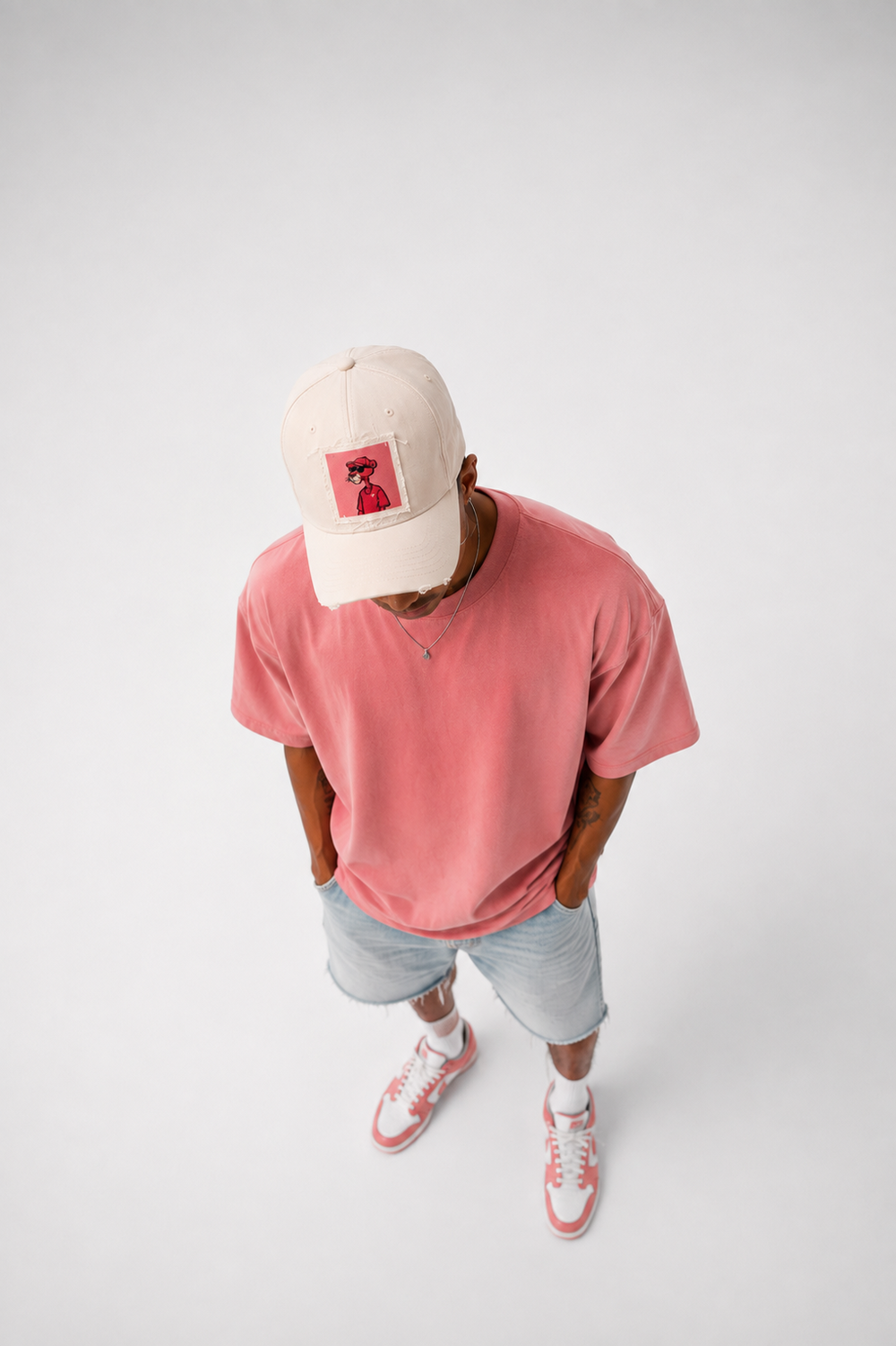 Sandfarbene Patch Cap mit Bildmotiv, kombiniert mit pinkem Shirt – Gestaltungsbeispiel